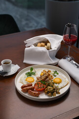 Delicious brunch spread with sunny side up eggs, sausages, and roasted vegetables beautifully arranged on a plate beside a refreshing drink.