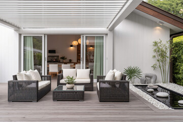 sleek backyard deck with dark wicker seating, ivory cushions, motorized pergola, zen garden elements