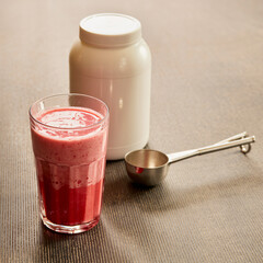 strawberry protein drink and supplement powder tub in a gym setting