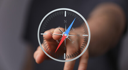 Close-up of a hand interacting with a digital compass, symbolizing guidance and direction.