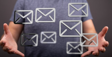 Image of a man holding multiple email icons, representing communication, inbox, messages.