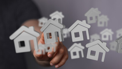 Hand points at floating house icons.  Perfect for real estate, property search, home buying, and mortgage concepts.