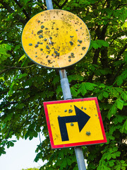 Old road sign indicating right turn in a rural area of Sweden surrounded by greenery