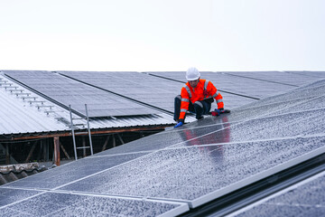 Engineers install solar panels on a wet rooftop during cloudy weather