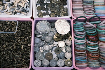 A collection of coins and bracelets are displayed in a pink container