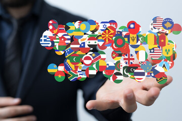 A businessman's hand displays a network of world flags, symbolizing global connections and...