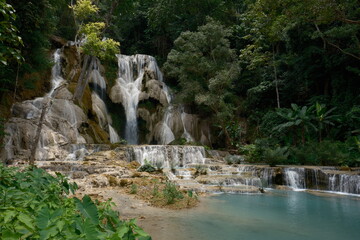 A waterfall is surrounded by trees and a pond