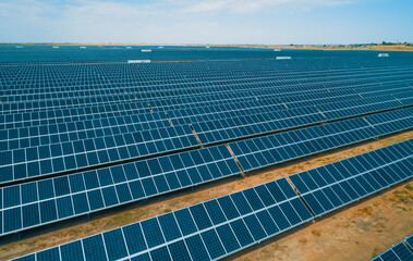 Expansive solar panel arrays under a clear blue sky in a vast renewable energy farm