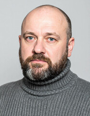 icy resolve; broad-shouldered Eastern European man with piercing blue eyes, full beard, thick gray wool sweater, and an expression of dignified stoicism
