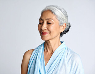 gentle wisdom; elderly Thai woman with silver bun, soft wrinkles, serene dark eyes, pale blue blouse, and ankle-length sarong in peaceful stillness
