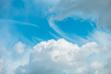 White cumulus clouds drifting across a vibrant blue sky create a picturesque scene filled with...