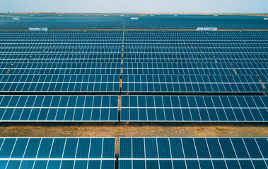 Large solar energy farm with numerous solar panels capturing sunlight in a wide open space during...