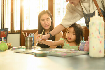 Collaborative art moment with a teacher, child, and parent engaged in creative learning