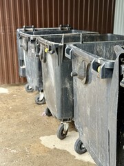 A Row of Industrial Waste Bins Equipped with Wheels for Easy Transportation and Use. A set of...