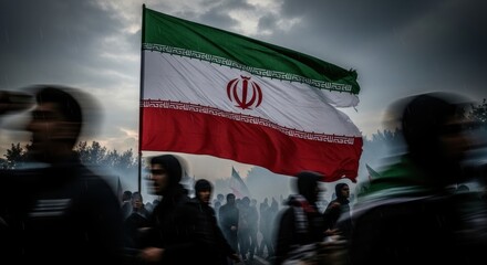 Naklejka na ściany i meble Large iranian flag waving against a cloudy sky with blurred crowd