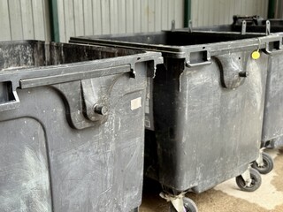 A Row of Industrial Waste Bins Equipped with Wheels for Easy Transportation and Use. A set of...