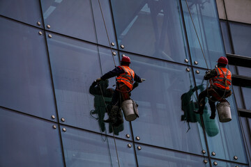 workers suspended on harnesses clean glass windows