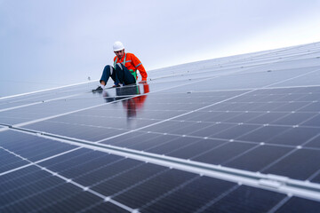 Engineer in safety gear standing on large solar panel rooftop