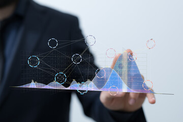 Stock photo of a businessman interacting with a digital interface showing graphs, charts and data...