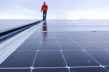 Engineer in safety gear standing on large solar panel rooftop