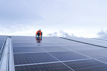 Engineer in safety gear standing on large solar panel rooftop