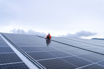Engineer inspects wet solar panels on a rooftop under overcast sky