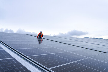 Engineer inspects wet solar panels on a rooftop under overcast sky