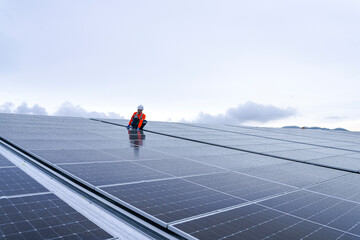 Engineer inspects wet solar panels on a rooftop under overcast sky