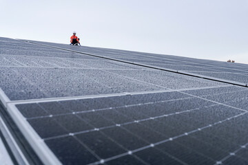 Engineer inspects wet solar panels on a rooftop under overcast sky