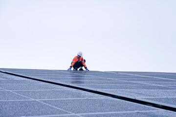 Engineer inspects wet solar panels on a rooftop under overcast sky
