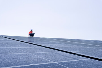 Engineer inspects wet solar panels on a rooftop under overcast sky