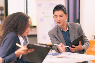 Two businessmen looking at computer screen with many graphs and charts and tablet for statistics, financial reports and planning revenue, profit or sales in office.