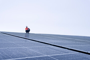 Engineer inspects wet solar panels on a rooftop under overcast sky