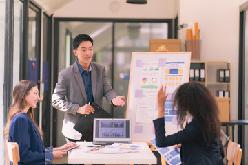 Group of business people discussing charts and graphs showing results of teamwork, analyzing financial data at desk in modern office about business strategy.