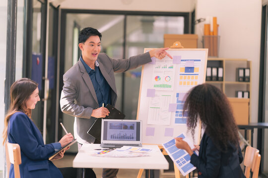 Group of business people discussing charts and graphs showing results of teamwork, analyzing financial data at desk in modern office about business strategy.