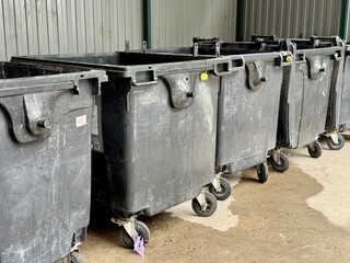 A Row of Industrial Waste Bins Equipped with Wheels for Easy Transportation and Use. A set of...