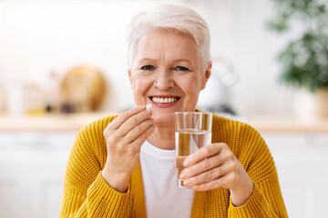 Supplements, vitamins, healthy lifestyle concept. Closeup of happy senior lady holding glass of...