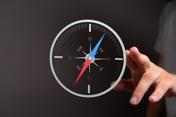 Hand holding a digital compass, showing navigation and direction. Ideal for travel, exploration,...