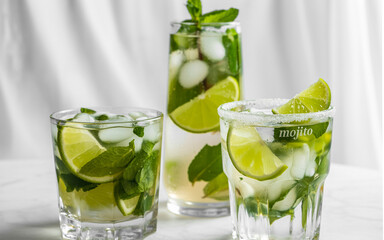 Refreshing summer drinks featuring mojitos with fresh mint limes ice cubes and simple elegant presentation for cocktails and refreshments