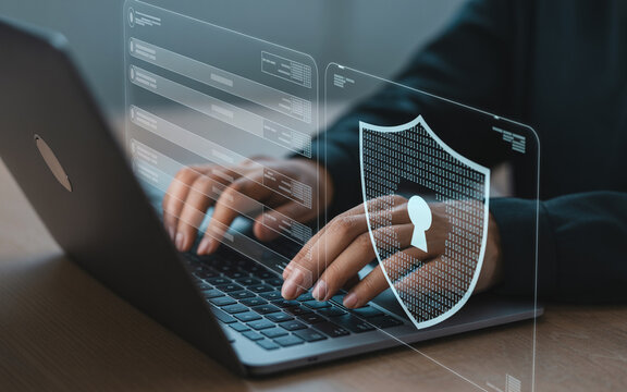 Person using laptop with digital security shield and interface concept of data protection and cybersecurity for safe computing.