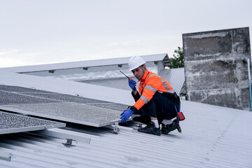 Naklejka premium Engineer installing solar panels on wet metal rooftop during cloudy weather