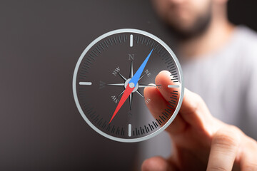 A businessman uses a digital compass to find direction, symbolizing strategic planning and guidance.