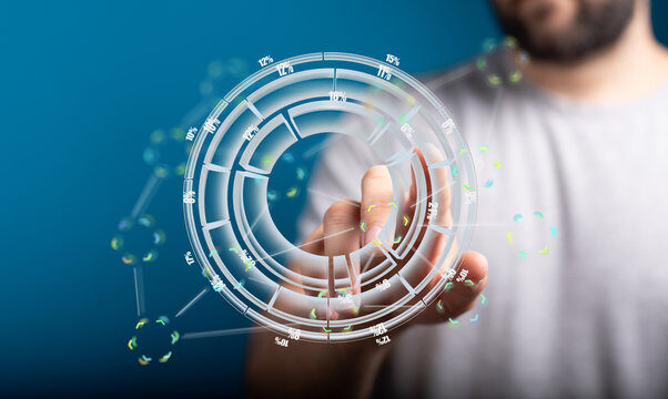 A man uses his finger to interact with a holographic circular data visualization interface showcasing business analytics and technology.