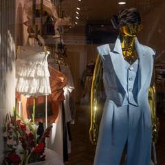 Mannequin in a Store Window Display, blue three-piece pantsuit with a vest on a gold mannequin