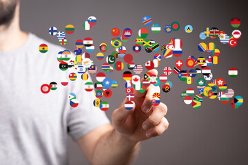 Image of a person interacting with a digital display of world flags, symbolizing global connectivity and international relations.