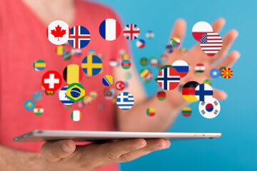 Image of a person using a tablet, surrounded by floating flags representing global communication...