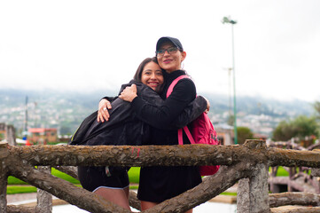 Two tourists hugging at scenic overlook with wooden fence