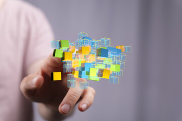 Abstract image of a hand interacting with a cluster of colorful 3D cubes, representing data or...