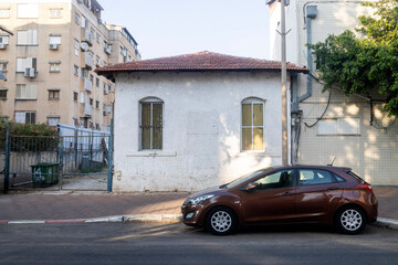 Petah Tikva, Israel, 12  JUNE 2025,  A Small old White House With A Red Tiled Roof Sits Next To A Parked Brown Car. Between last and future