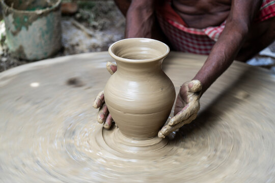 A potter shaping pot from lump of clay on potters wheel at pottery to sell